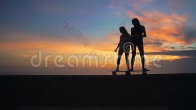 两个女朋友穿着短裤和运动鞋，在<strong>太阳升起</strong>的美丽天<strong>空</strong>下，在斜坡上骑滑板