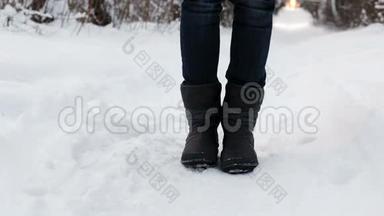 一个穿着靴子的女人冻僵了的腿在雪中从寒冷中跺脚。