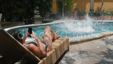 一个暑假的年轻人在他的女孩在甲板上做日光浴的时候，跳进蓝色的游泳池里