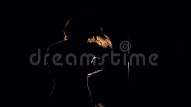 一个女孩在黑暗中用一个投影仪积极地<strong>打拳击</strong>的中镜头。