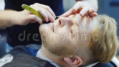 一个年轻人在理发店用危险的剃刀刮胡子