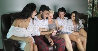 人们坐在沙发上用平板电脑看<strong>电视节目</strong>聊天，和年轻朋友交流