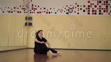 一位年轻漂亮的黑发女子在舞蹈室练习舞蹈