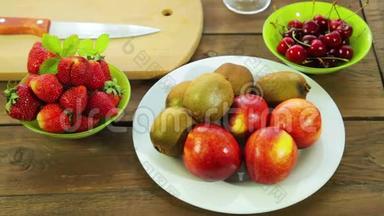 碗里的新鲜水果猕猴桃，桃子，草莓和樱桃放在木桌上..