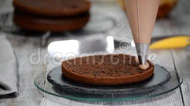 特写：饼干奶油以螺旋的形式出现在蛋糕上.. 巧克力海绵蛋糕加奶油。 准备蛋糕