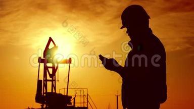 金日落时油田原油泵油田工人剪影。 工业、油田、人民和