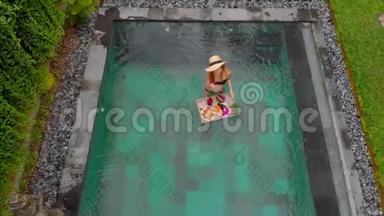 一位年轻的女游客在私人游泳池的一张漂浮的桌子上享用自己的私人早餐