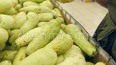 一个女人在蔬菜货架上的超市里买蔬菜和水果。 人类选择西葫芦。 慢动作，4k