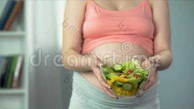 孕妇端着一碗<strong>富含维生素</strong>和营养的蔬菜沙拉