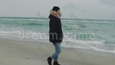 在寒冷的冬天，年轻漂亮的女人在海滩<strong>上走来走去</strong>。 慢动作