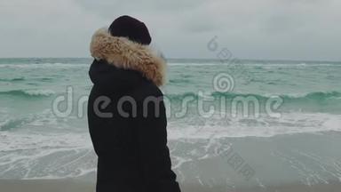 在寒冷的冬天，年轻漂亮的女人在海滩<strong>上走来走去</strong>。 慢动作