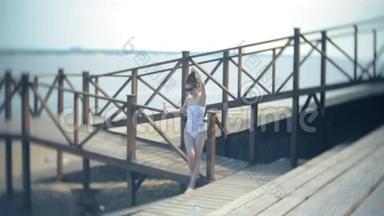 热辣的女孩站在沙滩上的桥上晒太阳.. 4k.