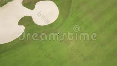 高尔夫球员在绿色球场上打球，从飞行无人机顶上看。 在高尔夫俱乐部球场上打球的人的鸟瞰