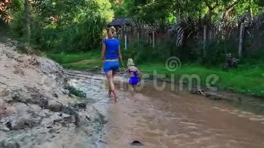 母亲的小女儿从沙滩上跳入浅溪