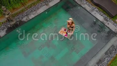 一位年轻的女游客在私人游泳池的一张漂浮的桌子上<strong>享用</strong>自己的私人早餐