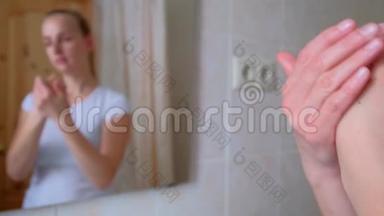 女人在浴室的手上涂抹保湿霜