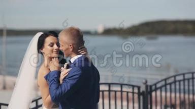 新婚夫妇在结婚典礼的那天站在码头上。 美丽的新娘和新郎互相欣赏。