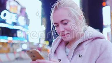 年轻女子穿着粉色外套在电话里打短信。 它<strong>应该</strong>在纽约曼哈顿时代广场