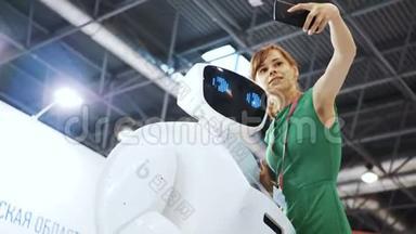 积极的女人用机器人做<strong>自拍</strong>。 女孩用机器人<strong>自拍</strong>。 漂亮女人在机器人后面重复动作