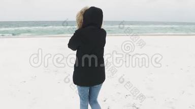 在寒冷的冬天，年轻漂亮的女人在海滩上<strong>走来走</strong>去。 慢动作