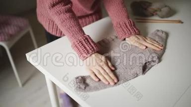 女人期待着<strong>宝宝看</strong>着躺在桌子上的针织毛衣。 手工制作的衣服