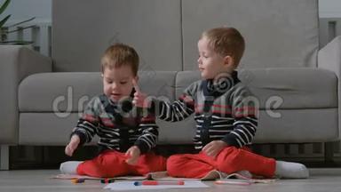 两个<strong>双胞胎兄弟</strong>蹒跚学步的孩子一起画坐在地板上的标记。