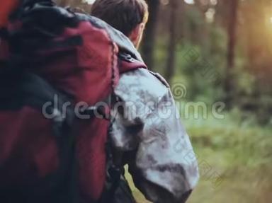 一个人背着一个穿着迷彩服的背包独自穿过森林。 猎人在探索这片领土。