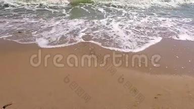 海浪与白色泡沫卷到沙滩。 晴朗温暖的夏日