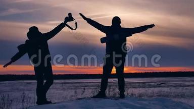 人们冬天的飞机剪影照片挥舞着手臂在天空中欢乐的雪阳光。 步行的游客组