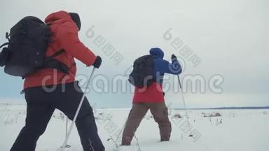 三个徒步旅行者带着徒步旅行杆、背包和雪鞋的后景。 带背包的快乐徒步旅行者小组