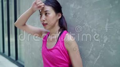 慢动作-健康美丽的年轻亚洲<strong>跑步</strong>女子饮水，因为在城市街头<strong>跑步</strong>后感到疲倦。