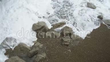 泡沫飞溅的海潮波浪用石头冲刷海沙海岸