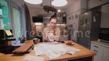 年轻女子坐在厨房的桌子旁，在购物后计<strong>算账</strong>单。 家庭账户部。