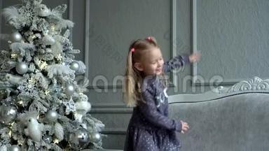 这个金发小<strong>女孩</strong>在<strong>圣诞树</strong>上的沙发上玩尾巴。 可爱的<strong>女孩</strong>在装饰的附近玩耍