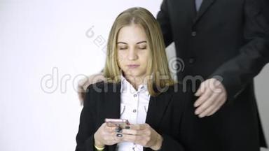 女商人在手机上自拍，雇员在做了很长时间的工作后，会<strong>按摩</strong>她的<strong>肩膀</strong>和脖子