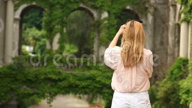 一个旅游`的女孩为一座扭曲着常春藤的古老城堡的美丽拼贴画拍照。