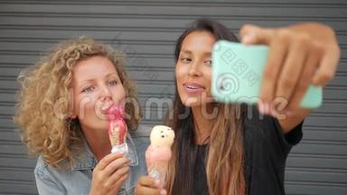 年轻有趣的混合种族女孩吃冰淇淋和自拍照片使用智能手机。 生活方式高清慢镜头