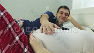 一个<strong>男人</strong>的手紧`抚摸着一个孕妇的<strong>大肚子</strong>。