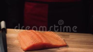 用刀在木板上特写生鱼片。 切制三文鱼前的多汁观赏