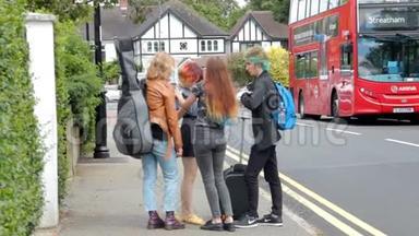 四个暑假的年轻人提着手提箱、吉他和背包站在汽车站附近。