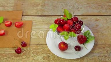 一张放在木制桌子上的白色盘子上是草莓和樱桃