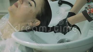 理发店。头部，侧视图。女人用长长的黑发洗油漆漂亮的女孩用油漆涂在客户的脸上
