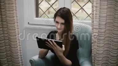 年轻漂亮的黑发女孩上网，并使用平板电脑。 有魅力的女孩在家休息。