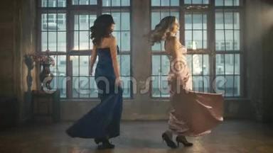 两个穿着晚礼服的漂亮女孩旋转着跳舞。 粉红色和蓝色的长裙。 很长一段时间。 金发女郎