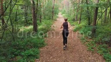 从后面的鸟瞰到在松树林中沿着小径奔跑的年轻女子