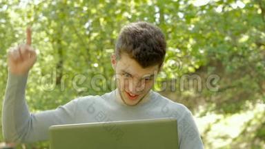 年轻的同志微笑着，在公园里用笔记本电脑工作