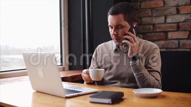 那个人在咖啡馆休息时打电话看着笔记本电脑