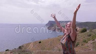 女人站在海边的山上，<strong>刮风</strong>的日子。 举起手来