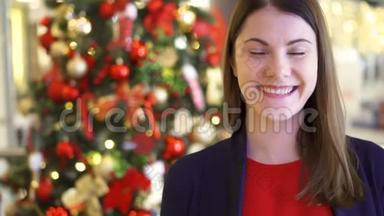 圣诞树上装饰的年轻女子的肖像。 漂亮的女人站着微笑