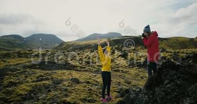 摄影师在山上为旅游妇女拍照。在冰岛的熔岩场拍照片的女孩。
